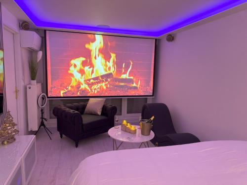Cette chambre dispose d'une cheminée, d'un lit et d'une télévision. dans l'établissement Loveroom de luxe avec jacuzzi sauna vapeur écran 300 cm, à Metz