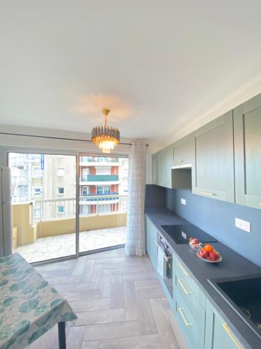 une cuisine avec des placards bleus et une grande fenêtre dans l'établissement Appart T2 refait à neuf 50m2, à Nice