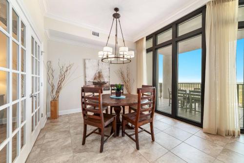 een eetkamer met een tafel, stoelen en ramen bij The Oasis at Orange Beach 1813 (formerly known as Phoenix West II) in Romar Beach