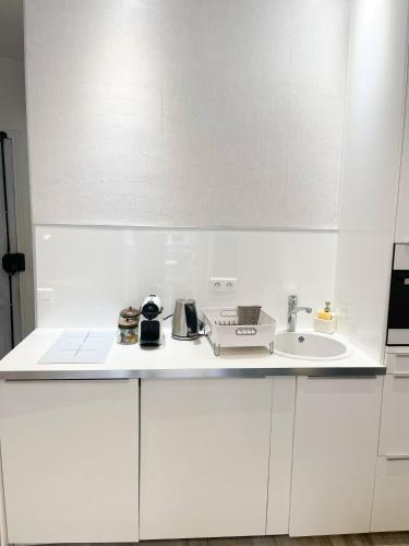 une cuisine avec des armoires blanches et un évier dans l'établissement Résidence Prestige Madeleine Opéra, à Paris