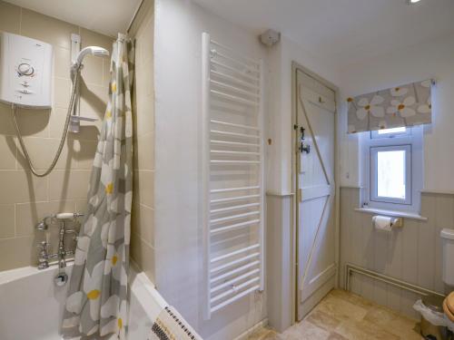a bathroom with a shower and a tub and a window at 1 Gabberwell Cottages in Kingston