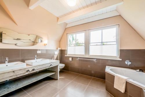 a bathroom with two sinks and a tub and a window at Ferienhaus Flieder in Liepe in Rankwitz