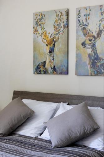 two paintings of deer on the wall above a bed at Mellieha Letcom Apartment in Mellieħa