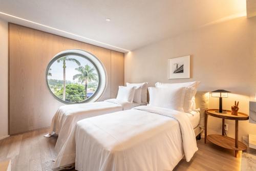 two beds in a room with a round window at Hotel Unique in Sao Paulo