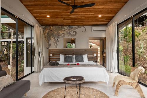 a bedroom with a bed and a couch and windows at Pandanus Lodge & Retreats Bungalow Heliconia in Cariblanco