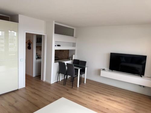 ein Wohnzimmer mit Tisch und Stühlen und einem Fernseher in der Unterkunft Ostsee Apartment mit Meerblick in Sierksdorf