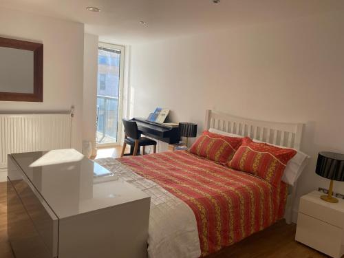 a bedroom with a bed and a desk with a piano at River view spacious apartment in London