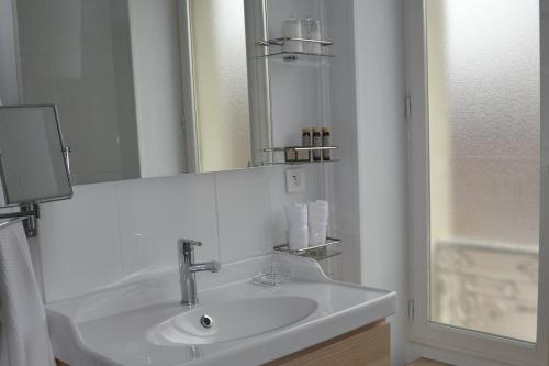 uma casa de banho branca com um lavatório e um espelho em Le Clos Sainte-Marie em Mesland