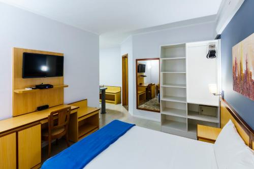 a room with a bed and a desk and a television at Hotel Augusta Boulevard in Sao Paulo