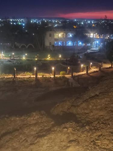 a field at night with a house in the background at Oasis Panorama in Bawiti