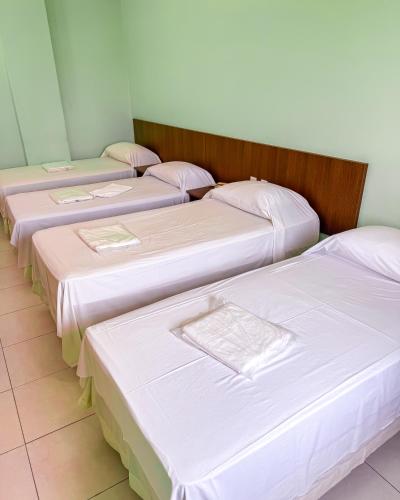 four beds lined up in a row in a room at Trindade Plaza Hotel in Trindade