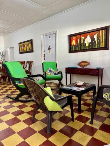 a living room with green chairs and a table at Helena's Place in San Andrés