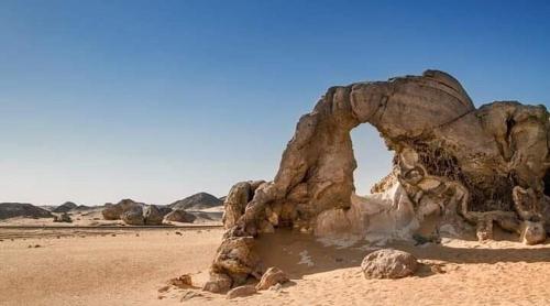 a rock formation in the desert with auddle of water at Oasis Panorama in Bawiti