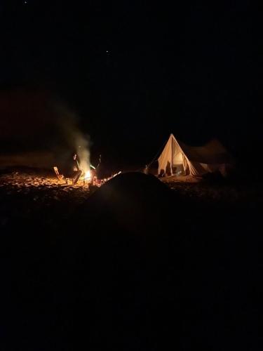 a man standing next to a tent at night at Oasis Panorama in Bawiti
