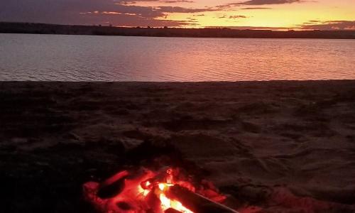 a camp fire on the beach with the water at Oasis Panorama in Bawiti