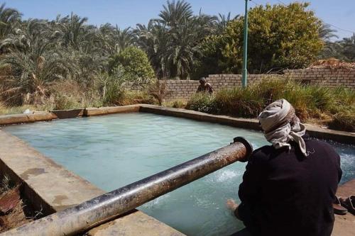 a person holding a pipe in front of a pool of water at Oasis Panorama in Bawiti