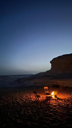 a table and chairs sitting on a beach at night at Oasis Panorama in Bawiti
