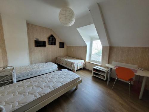 une chambre avec deux lits, un bureau et une fenêtre dans l'établissement Maison de bourg proche de la mer, à Damgan