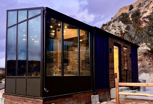 a black glass house with a mountain in the background at Wild Sage in Orderville