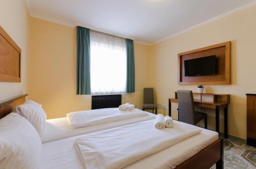um quarto de hotel com duas camas e uma secretária e uma televisão em Richter Pansion em Budapeste