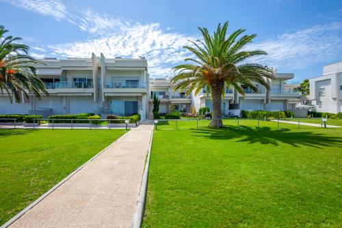 a building with palm trees in front of a park at White Pearl in Hanioti