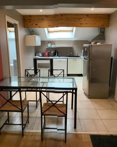 une cuisine avec une table, des chaises et un réfrigérateur dans l'établissement Le chardon lorrain, à Nancy