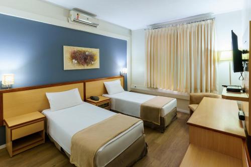 a hotel room with two beds and a television at Hotel Augusta Boulevard in São Paulo