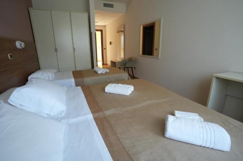 two beds in a hotel room with towels on them at Hotel Riggioni in Pozzilli