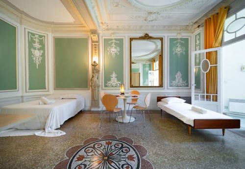 Cette chambre comprend 2 lits, une table et un miroir. dans l'établissement Le Versailles Unique et Charme, à Montpellier