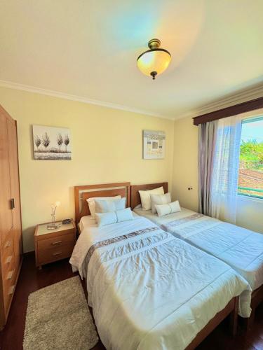 a bedroom with two beds and a window at The Sun Edge House in Ponta do Sol