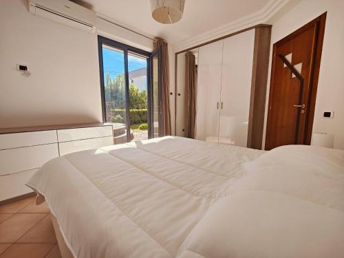 a bedroom with a large white bed and a large window at Maison Margot - Giardino e parcheggio privato in Volla