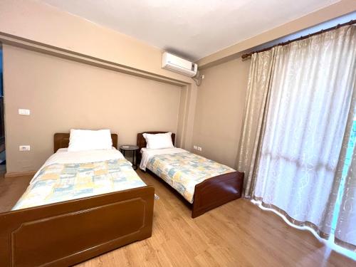 two beds in a room with a window at Garden Retreat Spiranca in Tirana