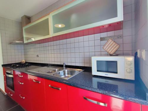una cucina rossa con lavandino e forno a microonde di Agroturismo Quinta De Travancela ad Amarante