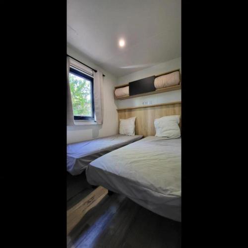 deux lits dans une petite pièce avec une fenêtre dans l'établissement Mobil Home Premium 3 ch Camping 5 Biscarrosse Mayotte F63, à Biscarrosse