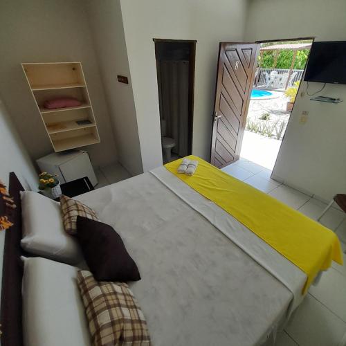a bedroom with a large bed with a yellow blanket on it at Pousada Barra Mansa in Pitimbu