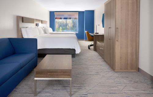 a hotel room with a bed and a blue couch at Holiday Inn Express & Suites Muncie Northwest by IHG in Muncie