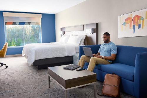 a man sitting on a couch in a hotel room at Holiday Inn Express & Suites Muncie Northwest by IHG in Muncie