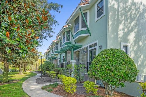 a building with green trim and trees next to a sidewalk at Book Your Summer Escape - TownHome by Disney! in Orlando