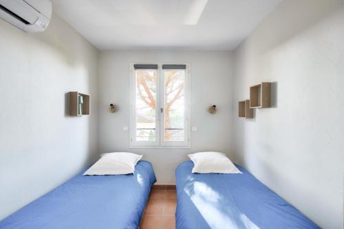 deux lits dans une chambre avec une fenêtre dans l'établissement Village Pont Royal en Provence - maeva Home - Maison climatisée 4 pièces 6 personnes - Sélection - super Home MAE-0411, à Mallemort