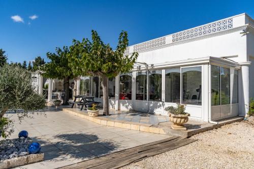 Cette maison blanche dispose de portes vitrées et d'une terrasse. dans l'établissement L'Hacienda Del Sud, à Béziers