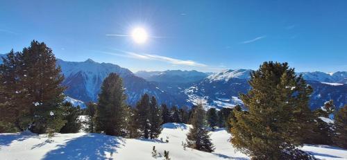 a snow covered mountain with trees and the sun in the sky at Apart Neunerhof in Jerzens
