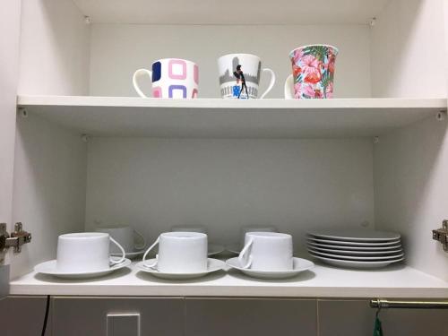 a shelf with plates and cups and dishes on it at Amenity at the Best of Aracaju 2 Beds in Aracaju