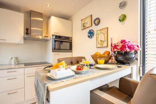a kitchen with a table with food and flowers on it at Maasparcje ecoLodge K2 Roermond in Roermond
