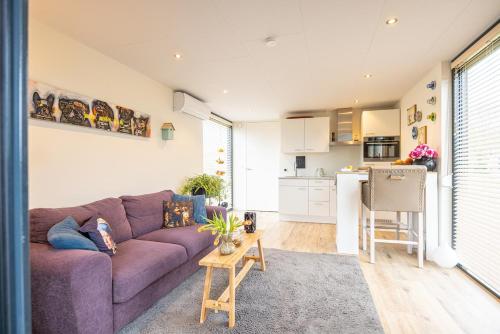 a living room with a purple couch and a kitchen at Maasparcje ecoLodge K2 Roermond in Roermond