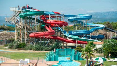 un toboggan aquatique dans un parc aquatique avec des gens dessus dans l'établissement Appartement Barcarès piscine chauffée, au Barcarès