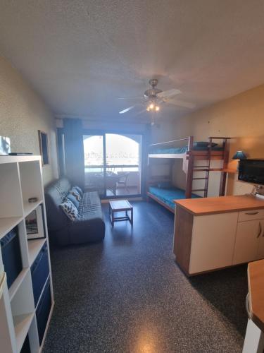 Cette chambre comprend un canapé et des lits superposés. dans l'établissement PISCINE CHAUFFEE, Vue imprenable Grand studio 4P Coudalère, au Barcarès