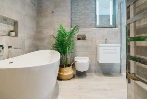 La salle de bains est pourvue d'une baignoire, de toilettes et d'une plante. dans l'établissement Heron House, à Newquay
