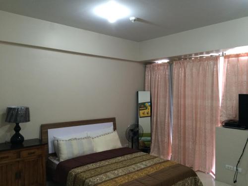 Schlafzimmer mit einem Bett, einem TV und einem Fenster in der Unterkunft Love This Place in Manila