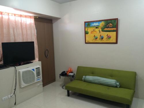 a living room with a green couch and a tv at Love This Place in Manila