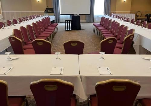 a conference room with white tables and red chairs at Inn on Prince Hotel and Conference Centre Truro in Truro